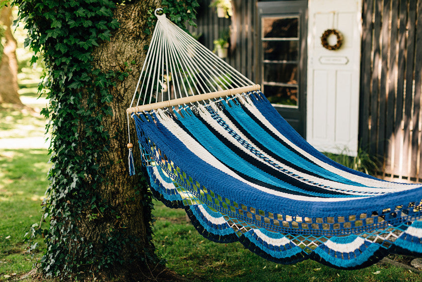 A blue, white and aqua hammock strung between trees