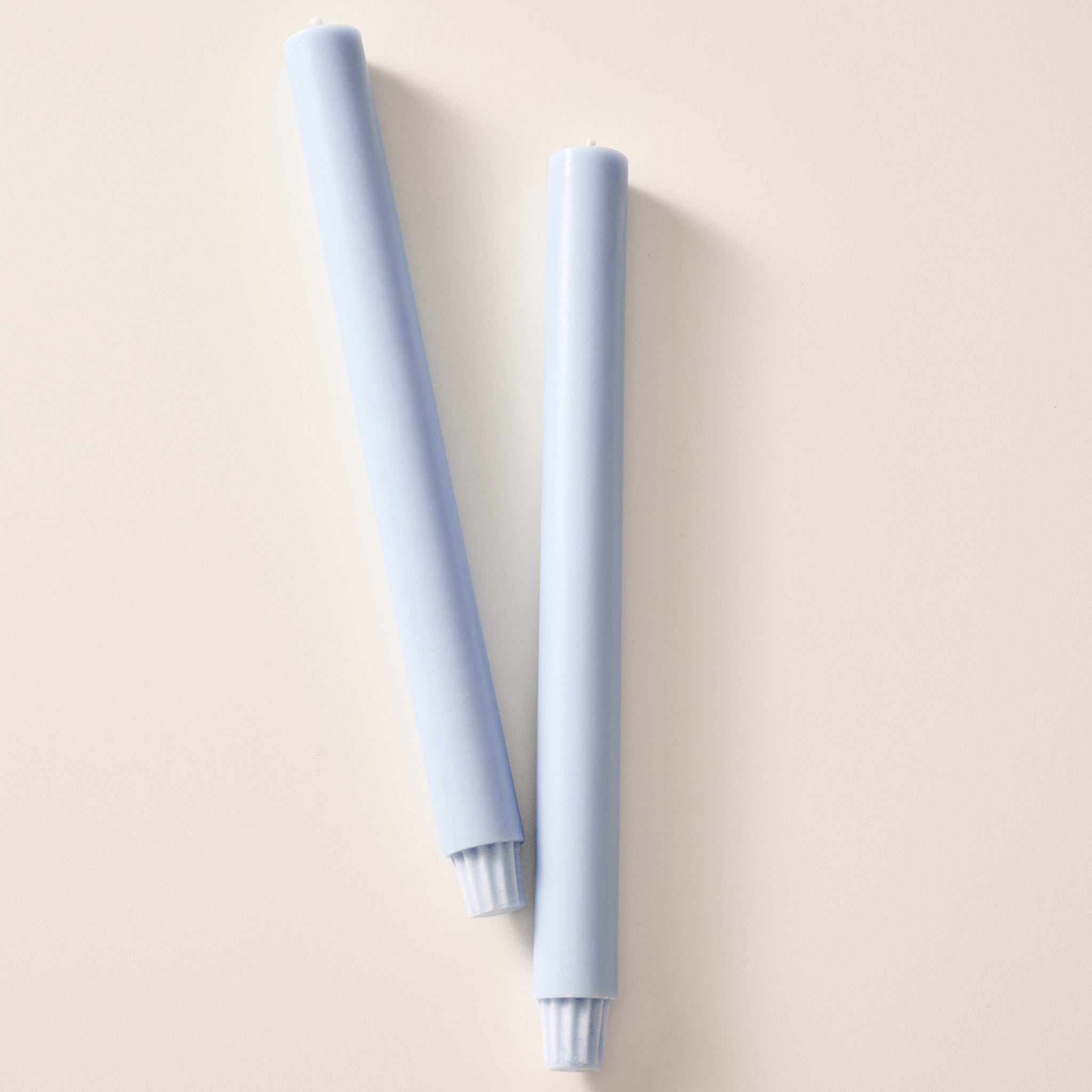 Two mint colored pillar candles with ribbed bases, laying flat on a white background.