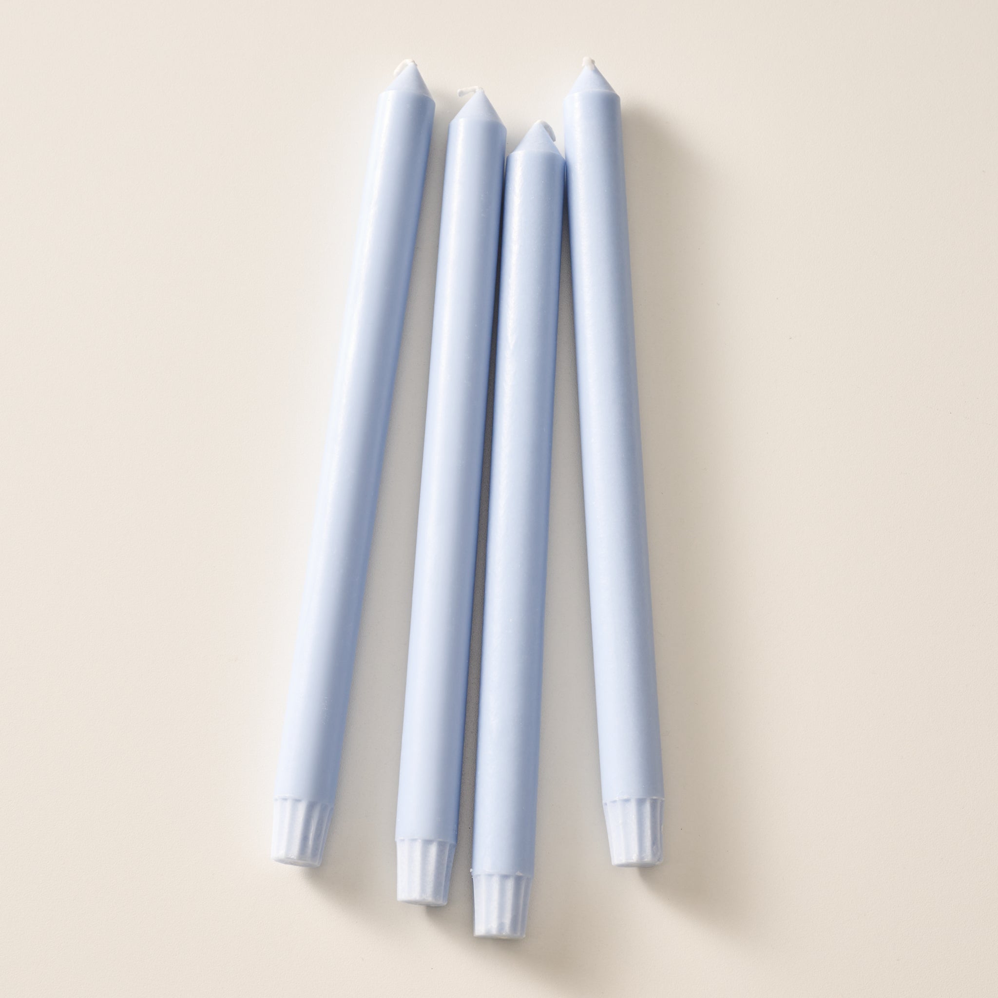 Four mint colored taper candles standing upright in a vertical row on a warm beige background.