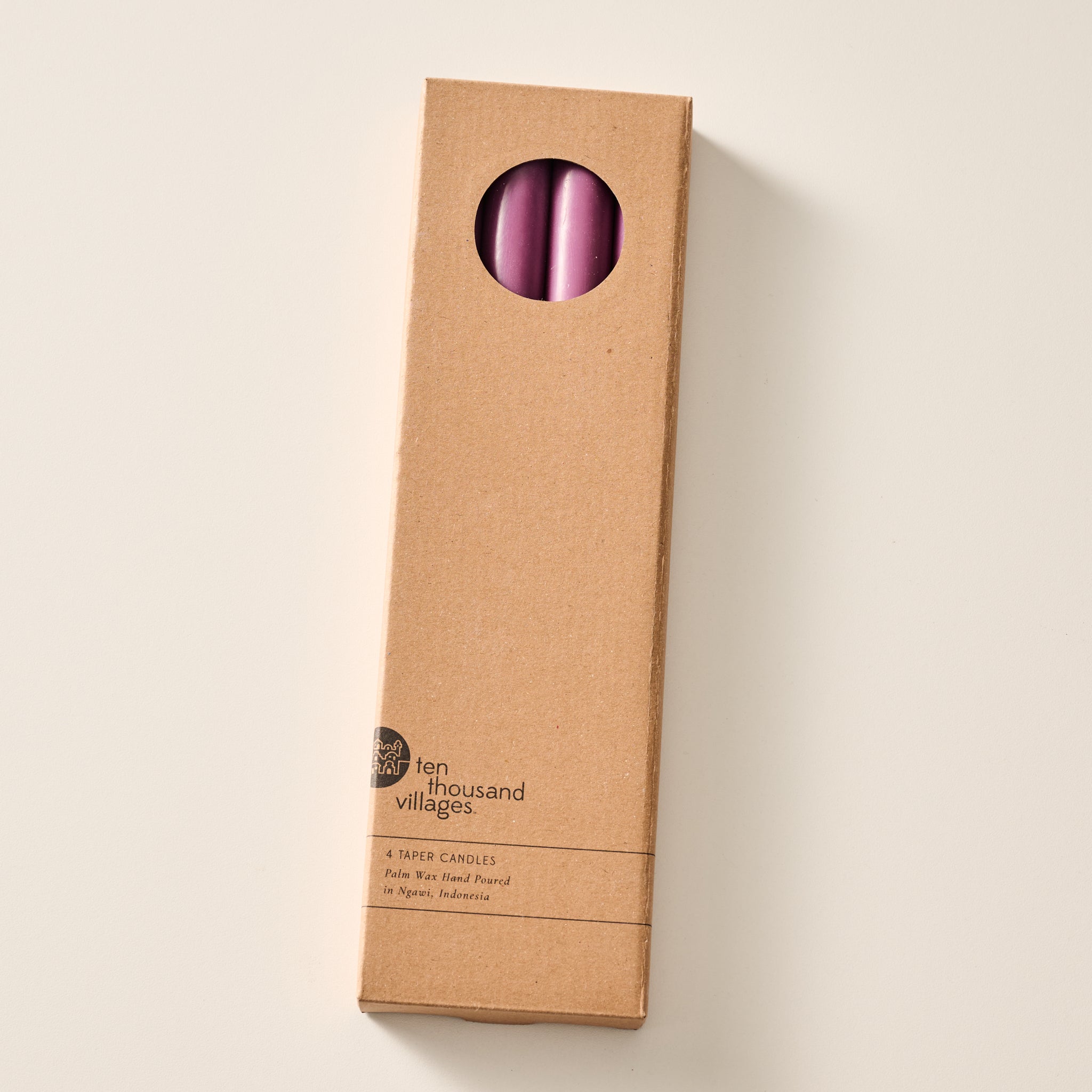 A tall, narrow cardboard box with a circular window display cutout at the top showing two blackberry candles inside, photographed on a clean off-white background. The box has printed text near the bottom including the brand name 'Ten Thousand Villages'.