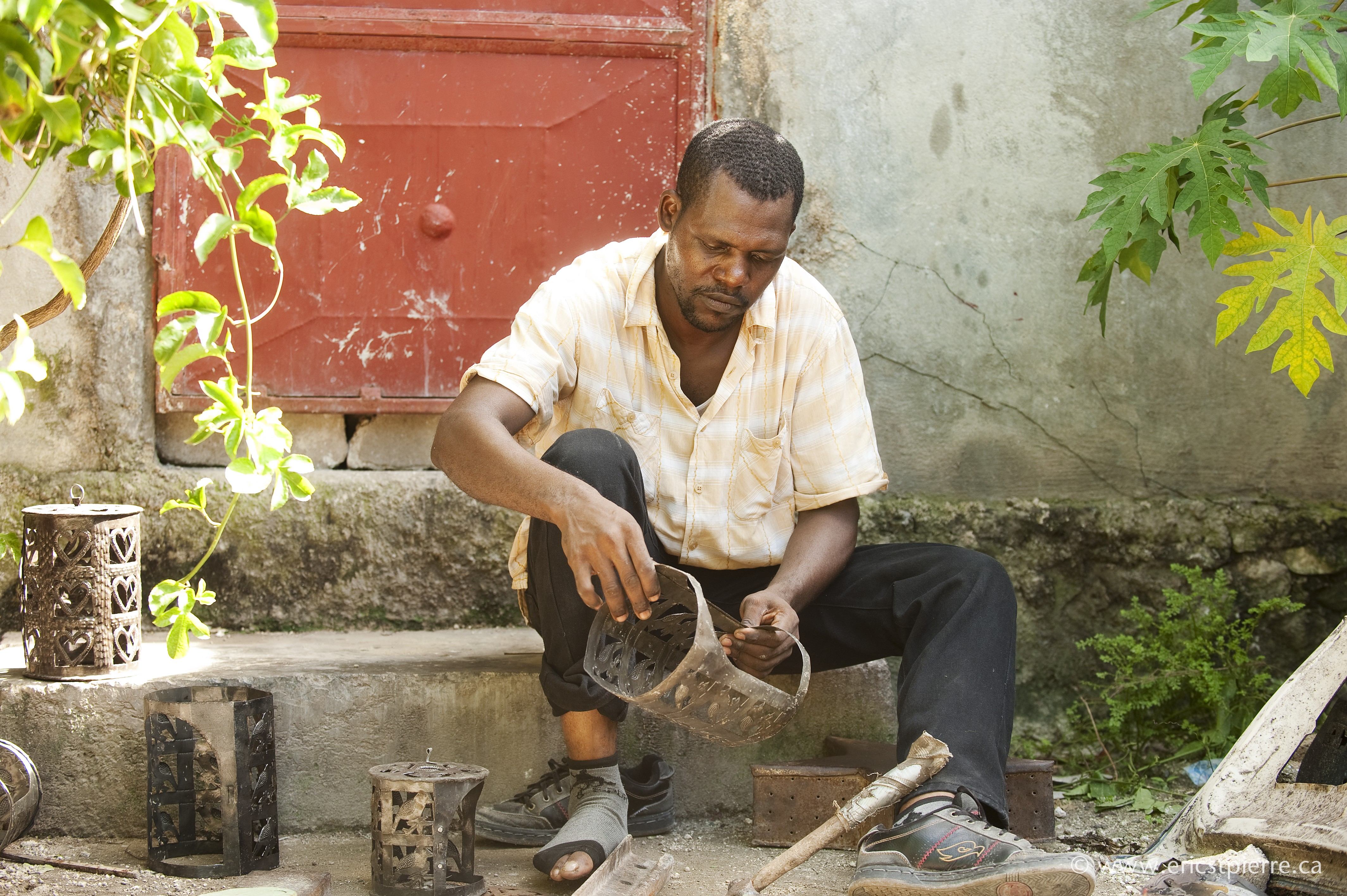 Haitian artisan inspecting his crafts
