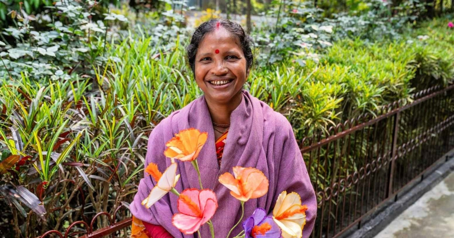 Prokritee Woman holding multicolored flowers she made.
