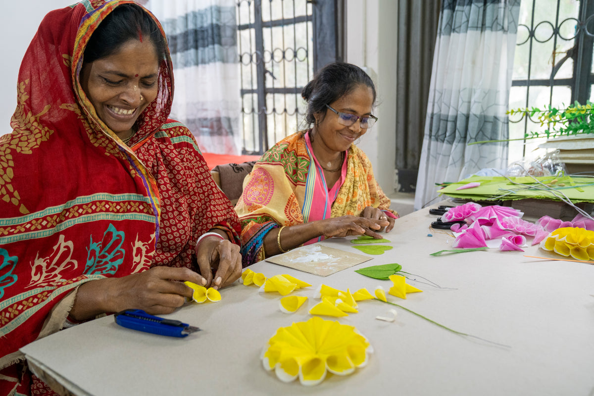 Two women working on flower arrangements at a table.